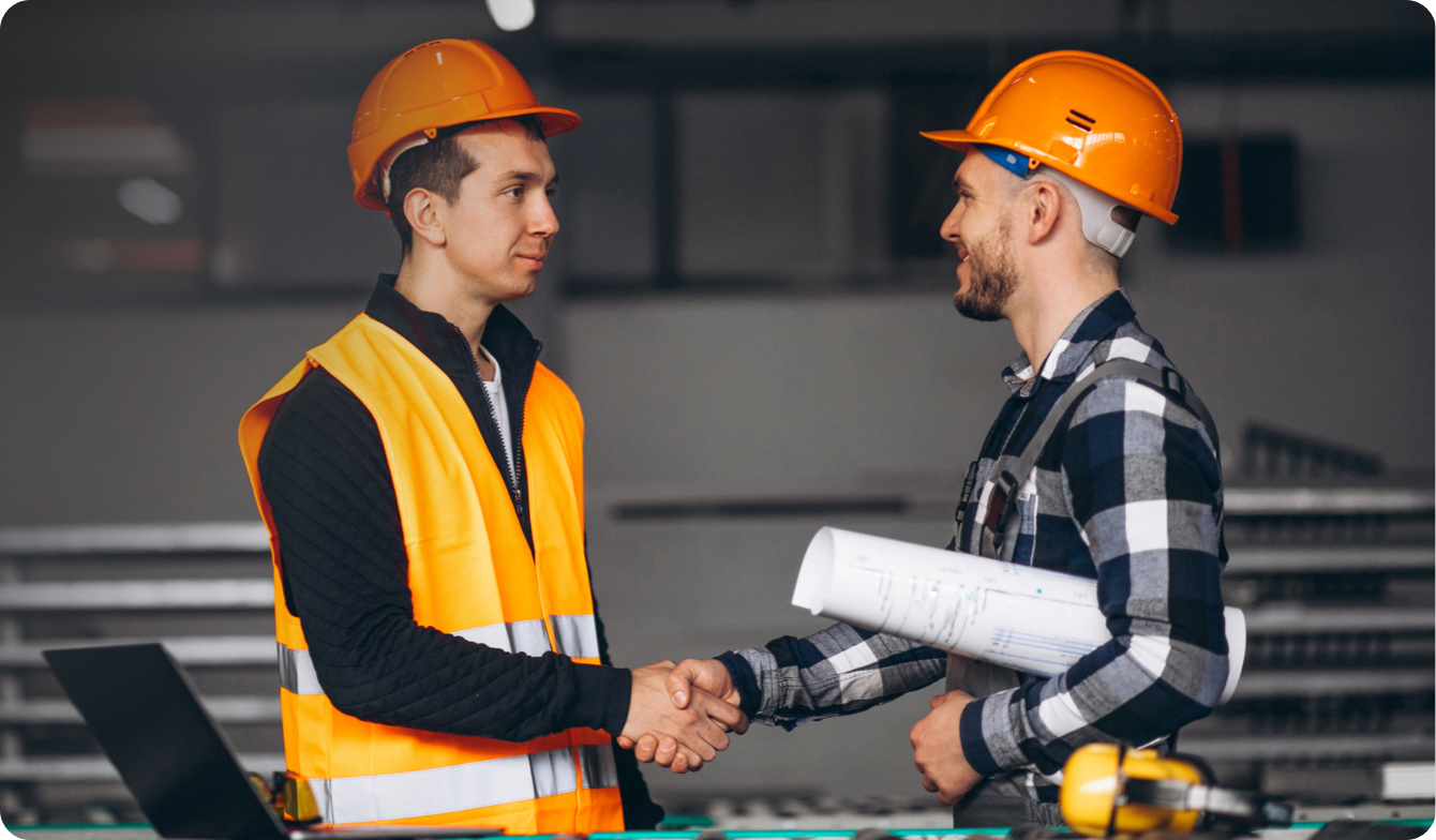 Two men in orange hard hats shaking hands.